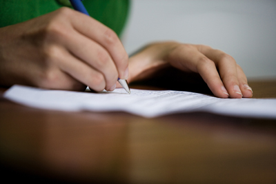 A picture of a person signing a contract on a desk.