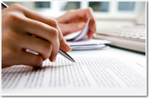 A person revising a typed paper with a pen.